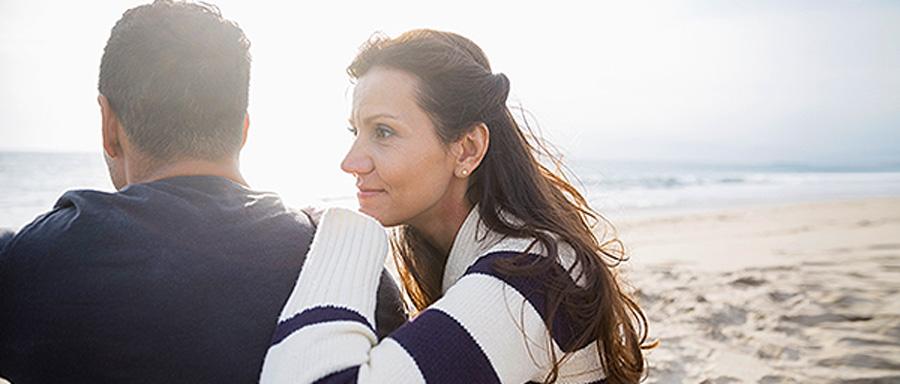 A man and a woman sitting together on a beach.
